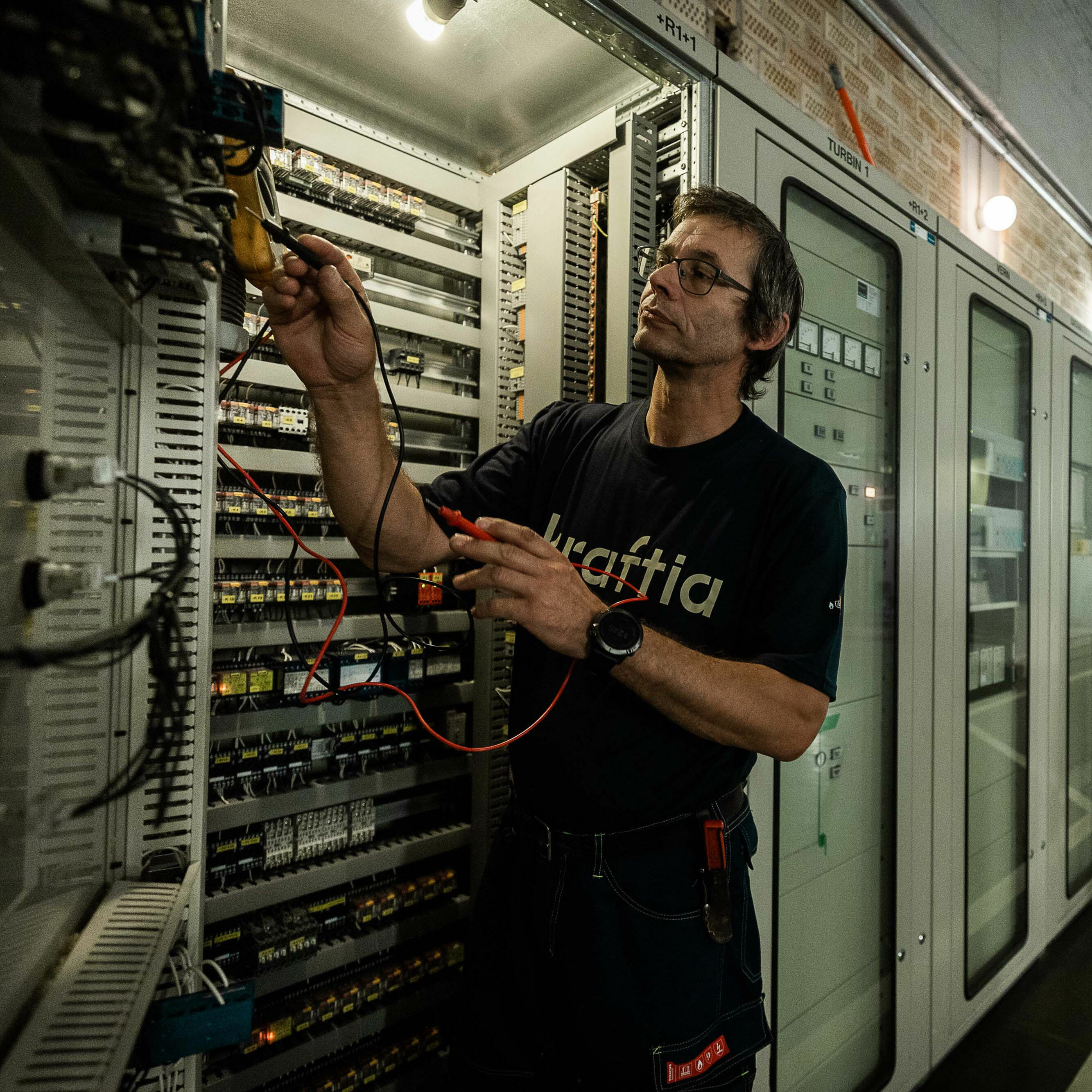 Foto: Person som arbeider med vedlikehold av elektriske kontrollpaneler.
